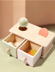 Detail of Montessori wooden object permanence box with pastel drawers and colorful coins