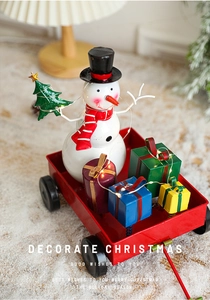 Close-up of a festive snowman figure with red metal cart and glowing LED fairy lights