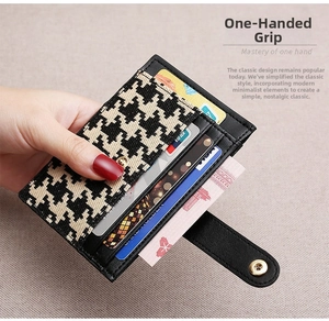 Macro detail of compact card holder showing black leather, houndstooth fabric, and snap button