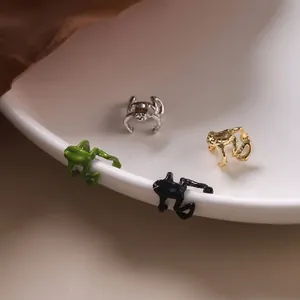 Gros plan de boucles d'oreilles grenouille en finitions métalliques or, argent et noir