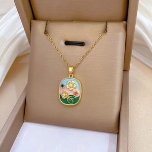 Detail of vintage enamel floral pendant necklace in champagne jewelry box with satin