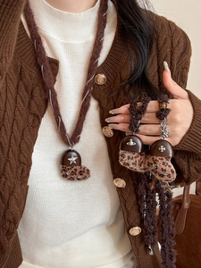 Dettaglio collana con pendente a croce e stivaletto in pelliccia sintetica leopardata