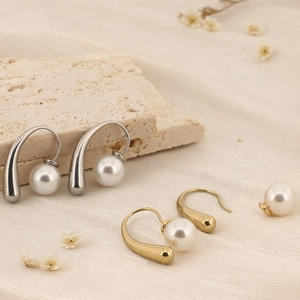 Détail de boucles d'oreilles perles vintage en or et argent sur un support en pierre
