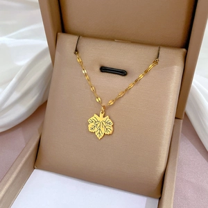 Gold maple leaf pendant necklace in titanium steel presented in a beige jewelry box