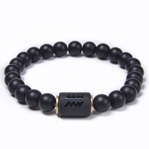 Detailed macro view of matte black onyx Aquarius zodiac bead bracelet with gold spacers