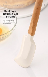 Detail of cream silicone spatula with beech wood handle next to eggs and kitchenware