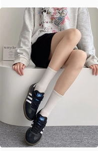Detailed view of black leather retro sneakers with white stripes and rubber sole
