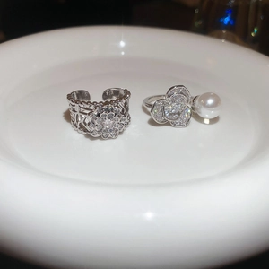Vue macro de bagues en argent avec fleurs en zircon et perles sur plateau blanc