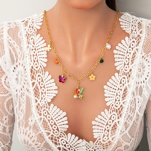 Detail of gold chain necklace featuring colorful butterfly, flower and pearl charms