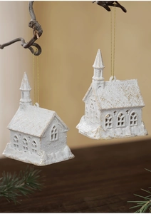 Detail of white and gold glitter church ornaments hanging on branches with festive lights