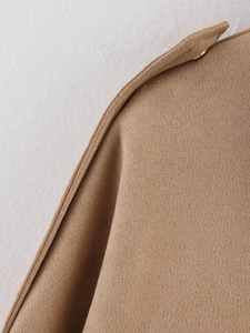 Detailed macro shot of tan knit texture and gold button on bomber jacket shoulder