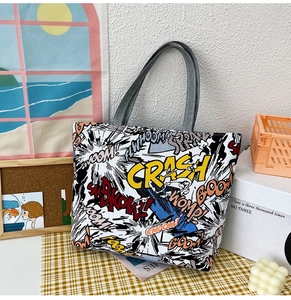 Close-up of comic print canvas tote bag with gray straps and pop art crash boom graphics