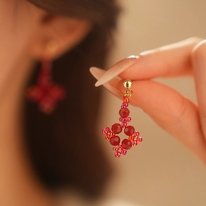 Close-up of red beaded flower earrings with gold metal accents on model's ear