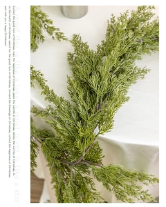 Detailed close-up of 180cm artificial cypress garland on soft white fabric background