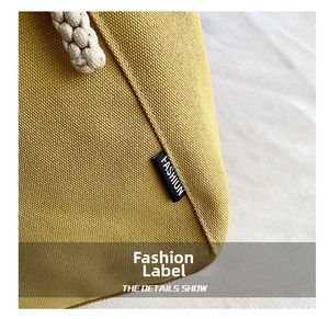 Macro shot of ginger yellow canvas bag featuring fashion label and braided rope handle