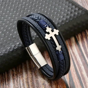 Macro shot of dark blue braided leather bracelet with silver cross and magnetic clasp