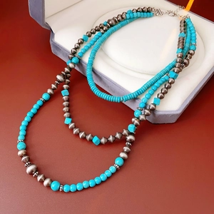 Dettaglio collana a strati bohémien con perline turchesi e argento su velluto grigio