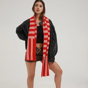 Knitted red and pink striped winter scarf worn by a model in a studio setting