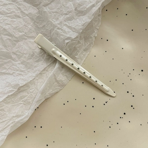 Detail of off-white matte duckbill hair clip with unique hollow circular pattern