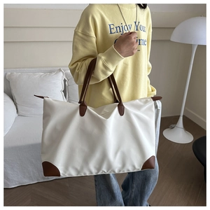 Detail of white waterproof Oxford tote bag with brown leather handles on a model