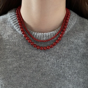 Détail d'un collier à double rang de perles rouges avec des perles dégradées sur un pull