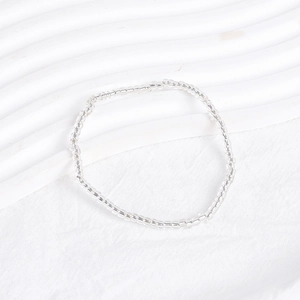 Macro shot of clear minimalist beaded bracelet on white textured fabric background