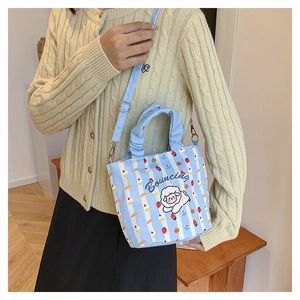 Detail of light blue striped canvas bucket bag with cartoon sheep and crossbody strap
