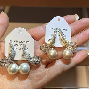 Close-up of bow knot earrings with micro-set zircon and round pearl drop details