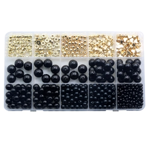 Macro detail of DIY jewelry set with gold star beads and black pearls in a plastic box