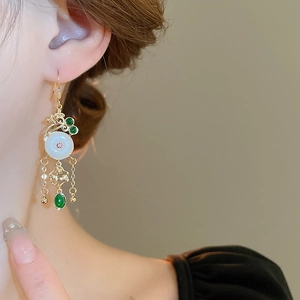 Detail of vintage style gold hook earrings with white disc and green drop pendants