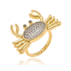 Macro shot of gold crab ring with sparkling clear crystals and black stone eyes