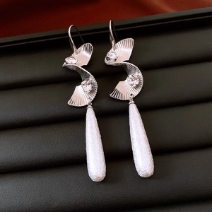 Macro shot of twisted silver earrings with zircon accents and matte teardrop pendants