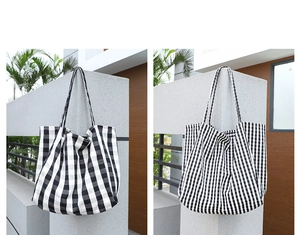 Detail view of large and small black and white checkered canvas tote bags on a wall