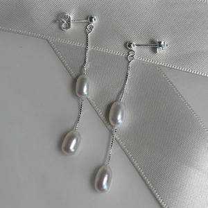 Macro detail of elegant long tassel earrings with lustrous freshwater pearls on white silk