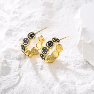 18K gold plated C-shaped earrings with black smiley face pattern on textured stone