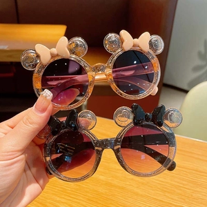 Detail of kids Minnie style sunglasses with round glitter frames and bow accents