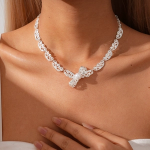 Silver hollow lace bow necklace with pearl accent shown on a model in high detail