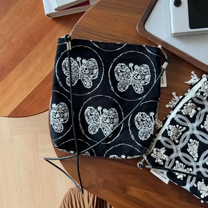 Detail of butterfly embroidery on black canvas phone bag with simple wish woven label