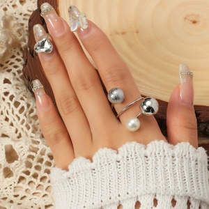 Adjustable multi-bead ring with silver spheres and white pearl on wood background