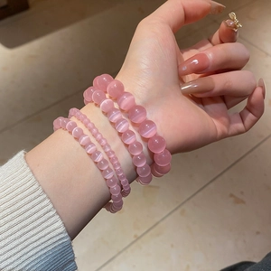 Detailed view of pink cat eye stone bead bracelets in various sizes on model wrist