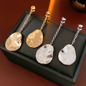 Vue détaillée de boucles d'oreilles asymétriques plaquées or 18 carats avec cristaux