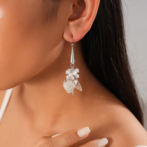 Detail of silver drop earrings with white pearls and metal leaf petals on model