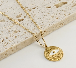 Close-up of golden evil eye pendant on textured stone background for women