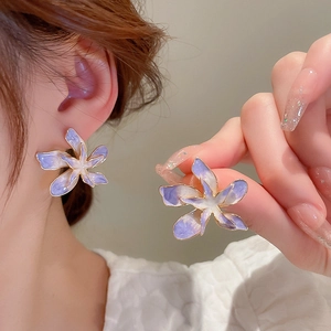 Gros plan de boucles d'oreilles fleurs en émail violet dégradé aux bords dorés