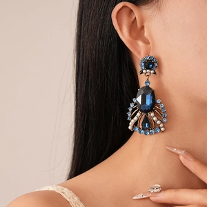 Vintage palace style drop earrings with deep blue crystals and pearls worn by a model