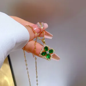 Close-up of a luxury gold-plated four-leaf clover pendant with green marquise-cut stones