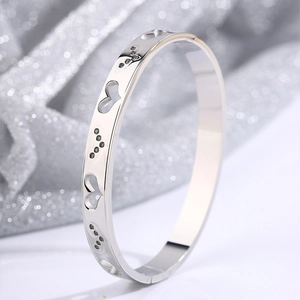 Macro side view of silver titanium steel bangle with hollow heart pattern details