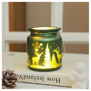 Close-up of frosted green glass Christmas lantern with deer and pine tree silhouettes