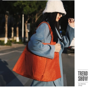 Fashionable orange tote bag with unique texture shown in a stylish street photoshoot