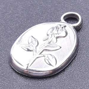 Macro shot of silver stainless steel oval pendant with a rose flower embossing